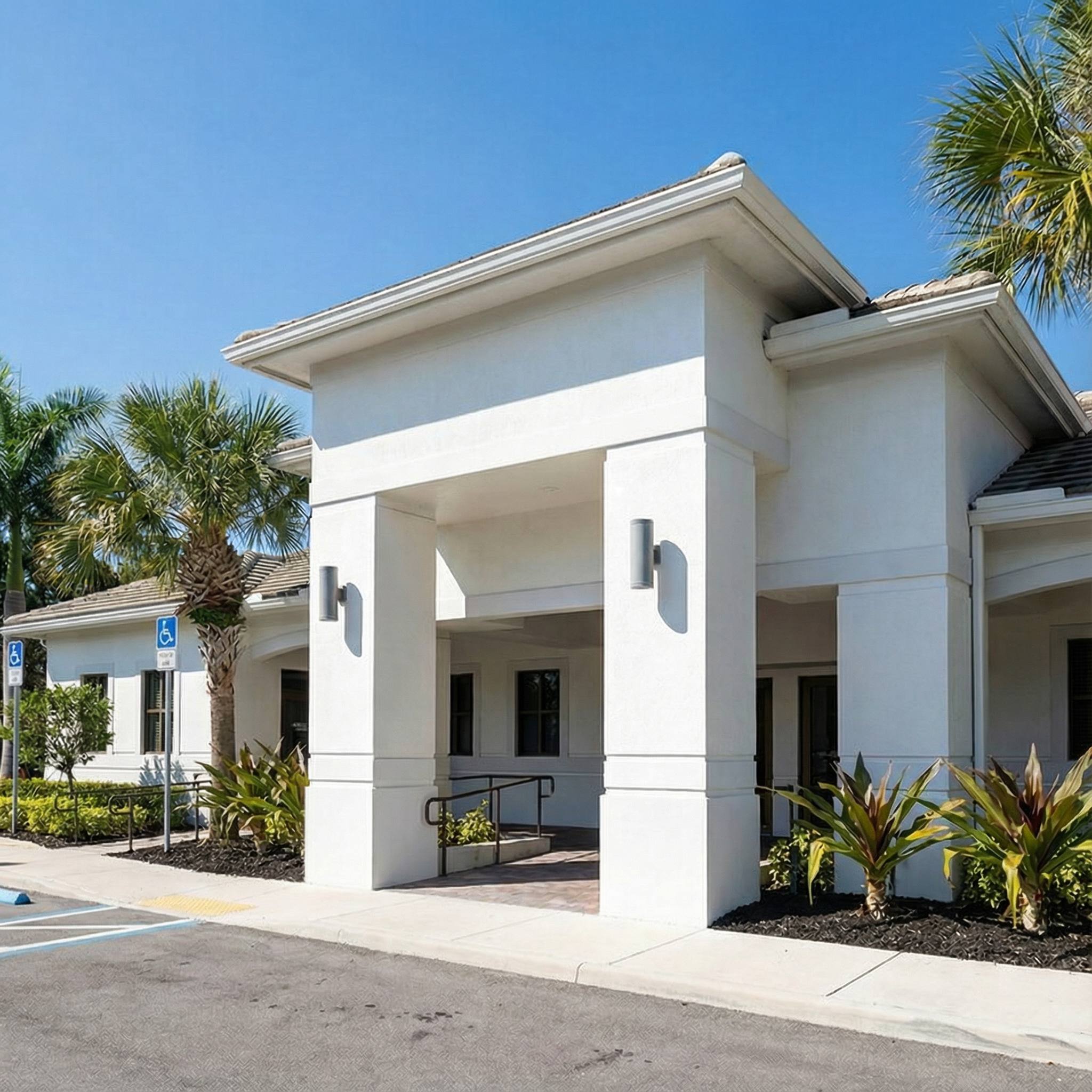 Eggnatz Weston Dentistry building exterior - Modern white stucco building with palm trees and covered entrance